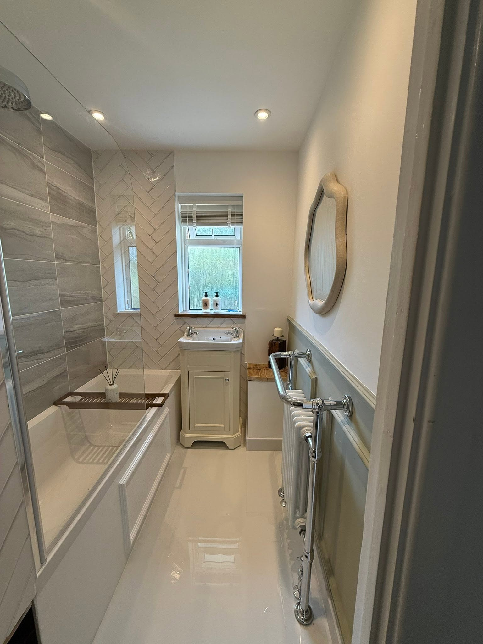 Bright finished bathroom with bath and radiator