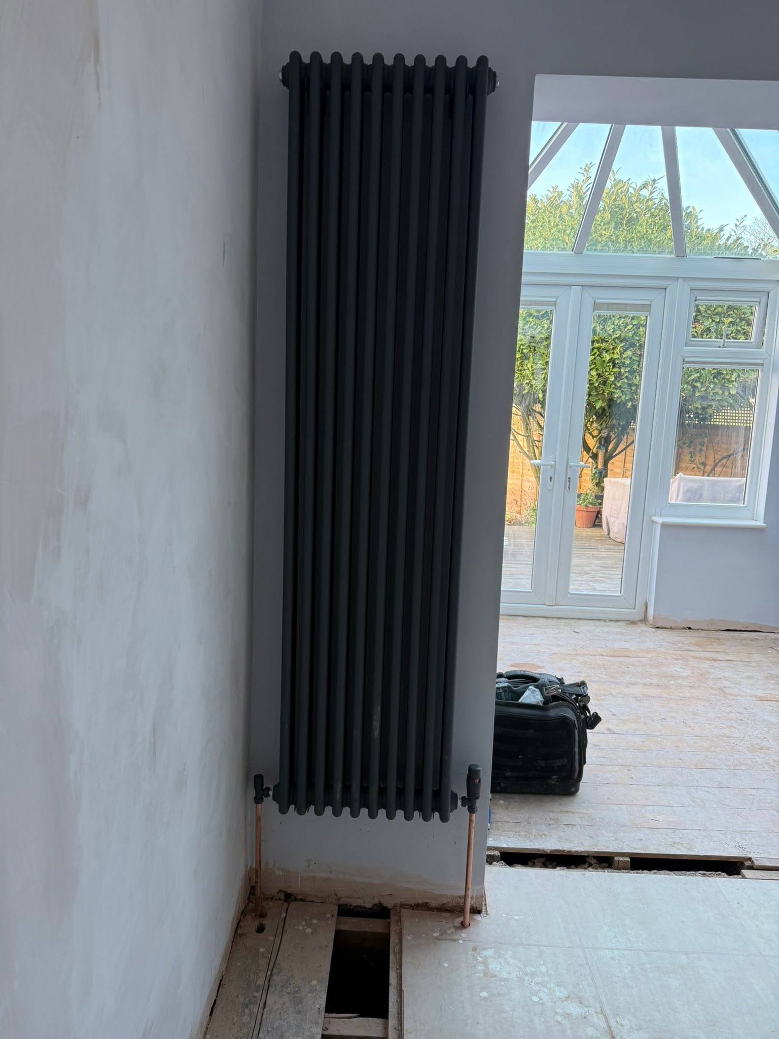 Black vertical radiator installation during renovation