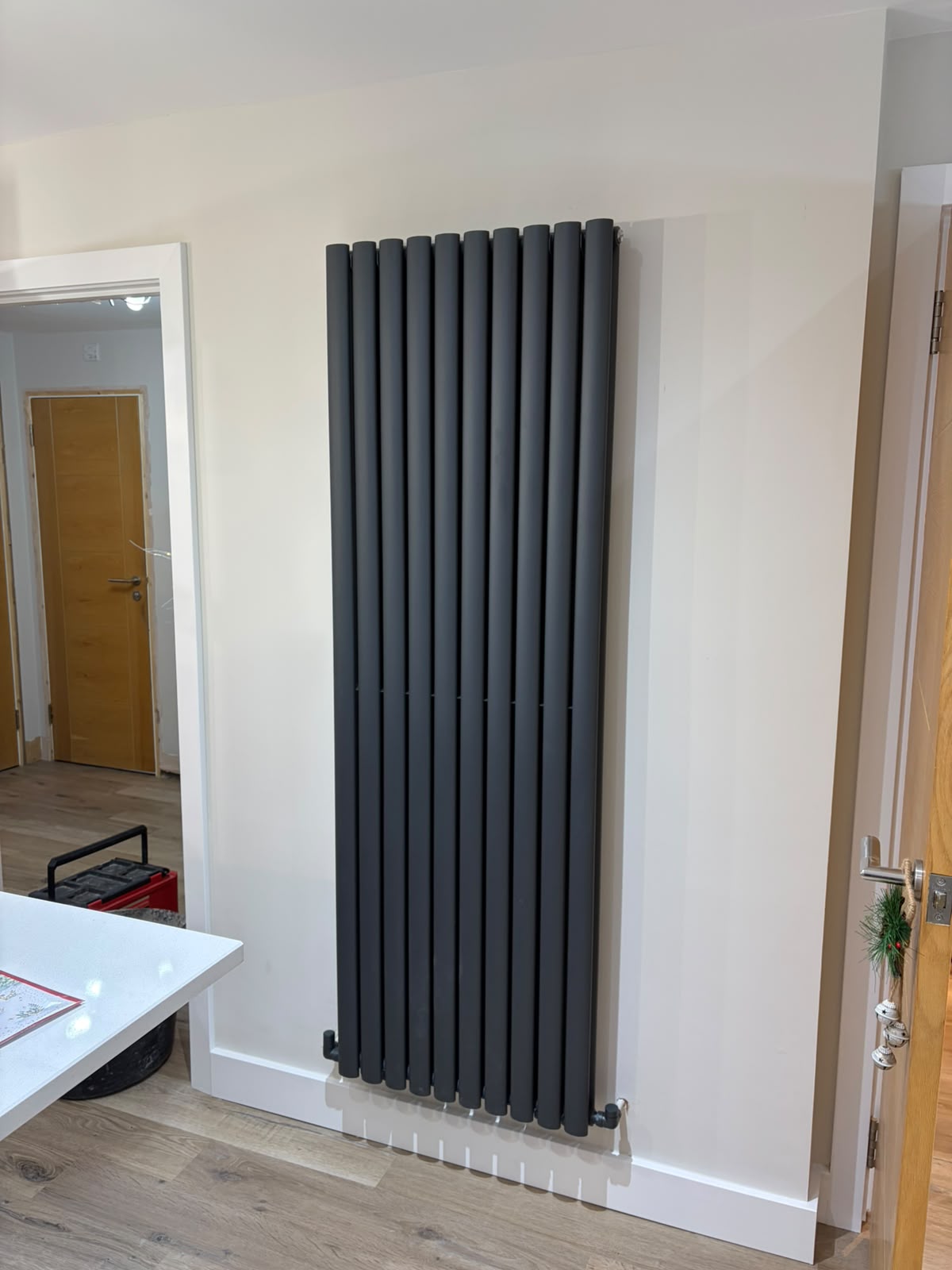 Tall black designer radiator fitted to a finished wall